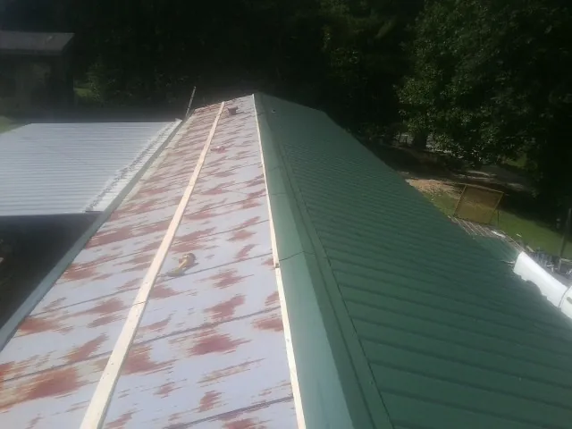Old rusted panels beside newly installed green metal roofing — Wind Damage Roof Repair by Roofing Brothers in George West