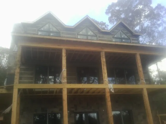 Dormers and porch framing on a large log home under construction — Roof Coating work by our crew in George West
