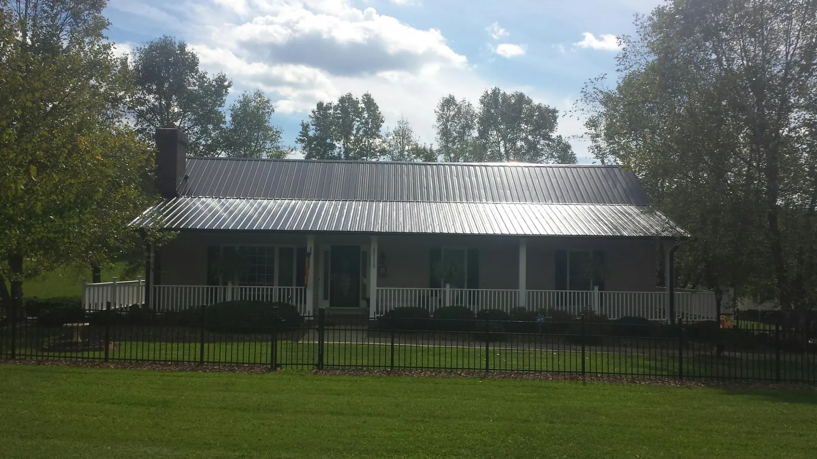 Gray metal roof on a brick ranch with a full width front porch — Gutter Guard Installation work by our crew in George West