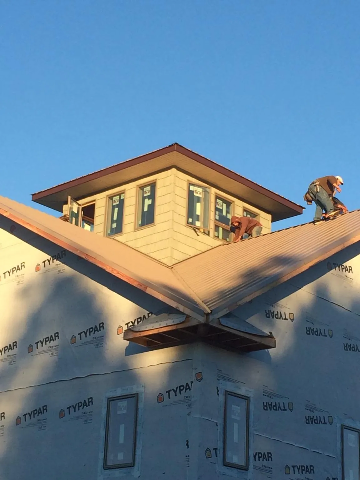 Roofers working around a rooftop cupola on a new metal roof at sunset — Roof Waterproofing in George West by Roofing Brothers
